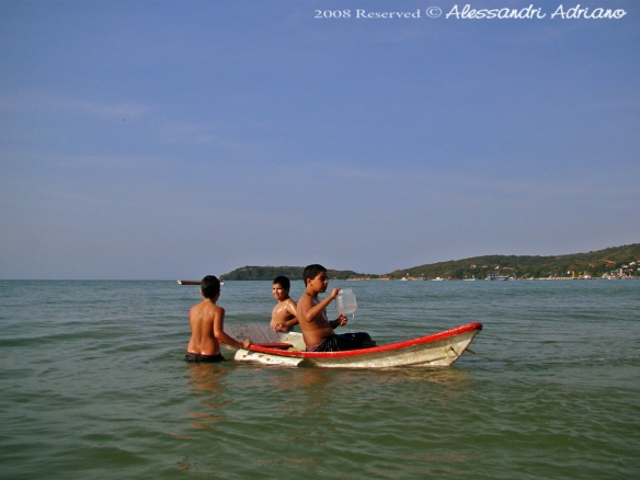 Garotos brincam com pequena canoa de fibra na praia de Manguinhos, Búzios, Rio de Janeiro (Desconhecido, Ayron e Eric).